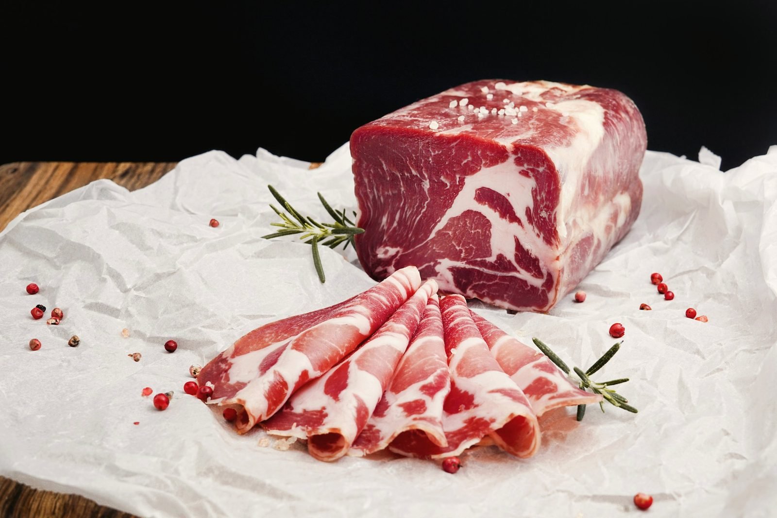 A trimmed beef chuck roll and thin slices resting on white butcher paper