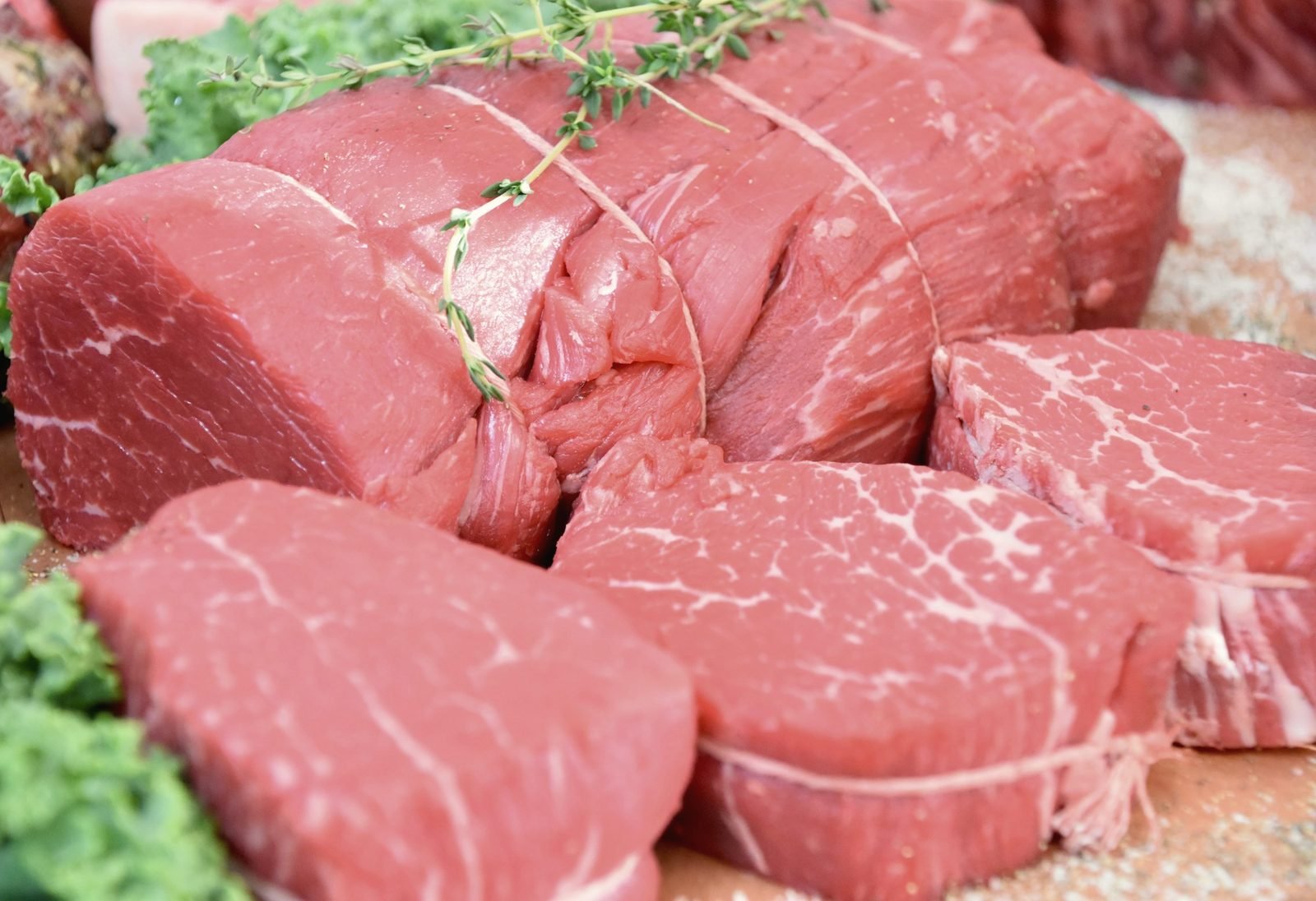 A whole beef tenderloin tied with twine beside cut filets